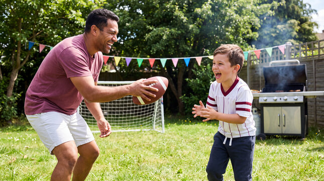 Father and son passing a football on a bright backyard lawn for Big Game Party lifestyle imagery.