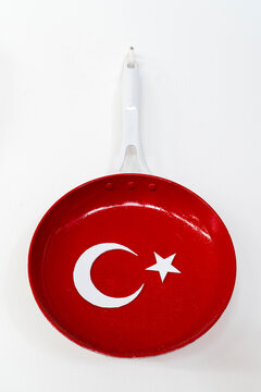 Red frying pan with Turkish flag pattern hanging on a white wall in a restaurant