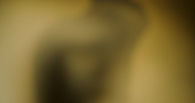 Blurred silhouette of a man with his hand near his mouth, casting a dark shadow on a warm yellow wall, in a conceptual image of depression, sadness and loneliness. 4K.