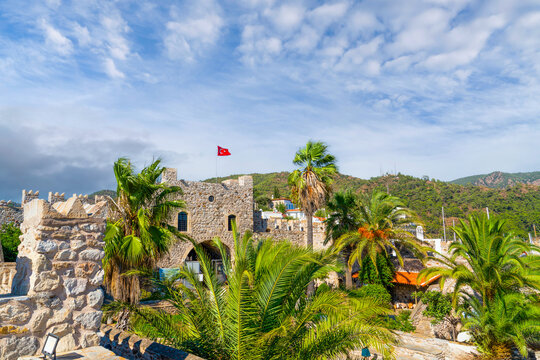 Historic Marmaris castle with Turkish flag and tropical palm trees under blue sky, Mugla, Turkey