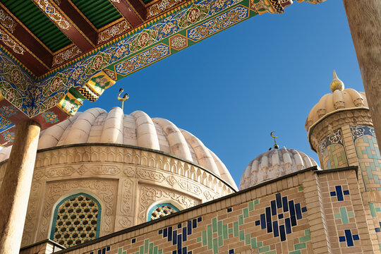 Ribbed domes and ornate painted ceiling of Hazrat Khizr mosque in Samarkand, Uzbekistan. Intricate tilework and carved stone details under a clear blue sky, ideal for travel and cultural publications.