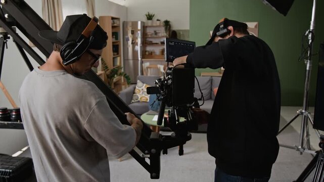 Caucasian young adult cinematographers operating professional camera on jib crane in studio set. Ideal footage for video production marketing, filmmaking tutorials and cinema equipment advertising