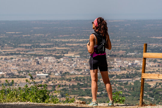 Female hiker looking down at the town from above, Sanctuary of Sant Honorat, Llucmajor, Mallorca, Balearic Islands, Spain