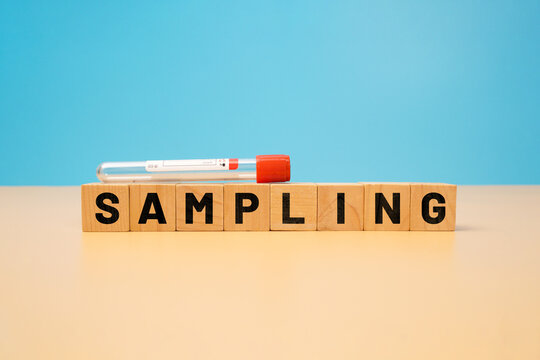 Laboratory specimen tube above wooden blocks spelling sampling on a peach surface against a blue background, representing sample collection and testing.