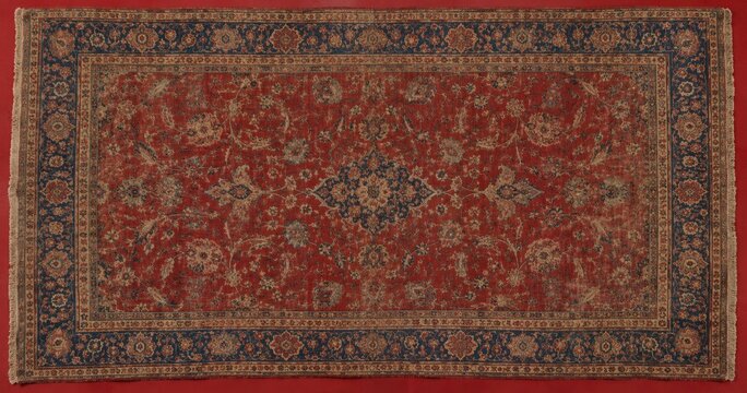 Intricate antique Persian rug with detailed floral patterns and a rich red and blue color palette for interior decor.