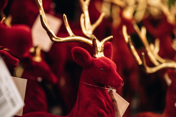 Red velvet reindeer decoration with golden antlers among festive ornaments and gift tags in a warmly lit holiday display © standret