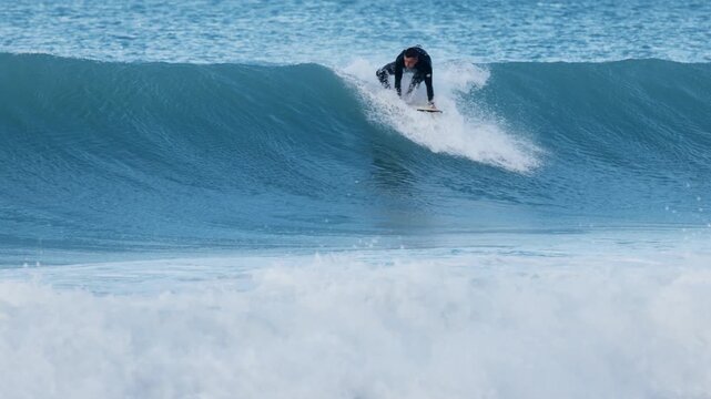 Surfer man ride on surfboard and jumped over a wave.