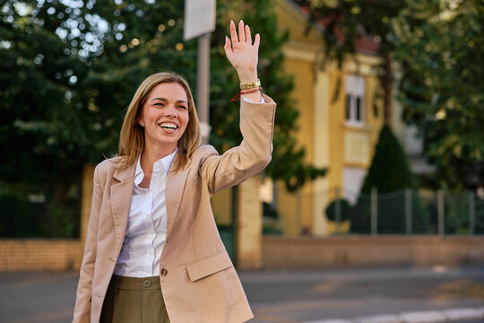 Waving businesswoman offers a welcome on a city street