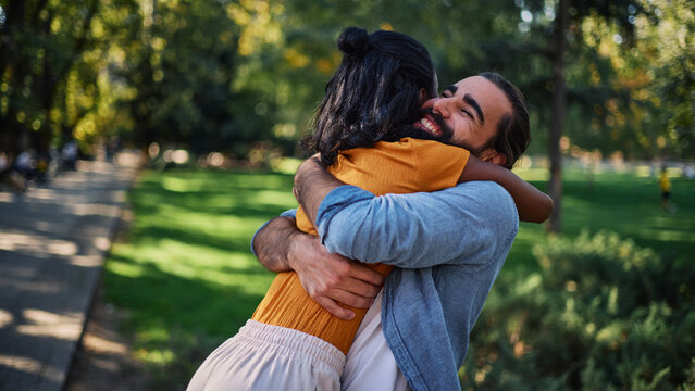 Couple hugs together in a sunny park during an outdoor date