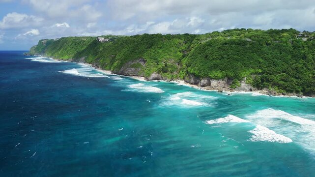 Scenic coastal landscape with green cliffs and luxury beach with ocean and waves. Drone view