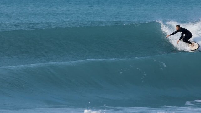Surfer man on surfboard surfing on ocean wave. Slow motion
