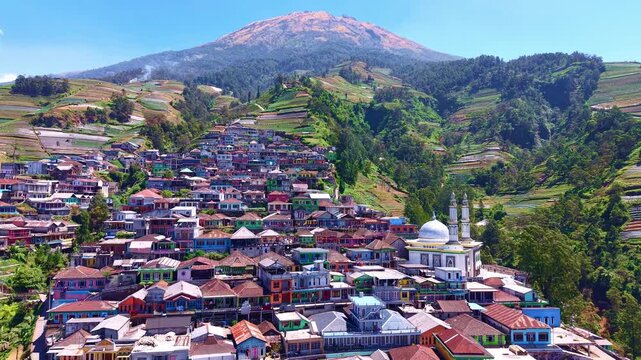 Aerial view of a tightly packed mountain village under a blue sky. Ideal for tourism, landscape documentation, and highland travel projects. Nepal Van Java, Indonesia.