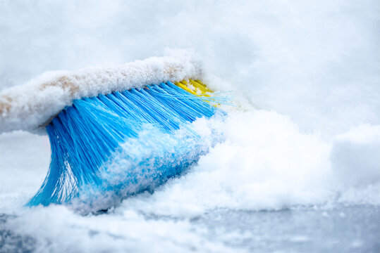 Removal snow from the car roof with blue brush in winter.