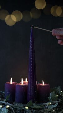 Hand lighting purple Advent calendar candle with numbered days countdown.