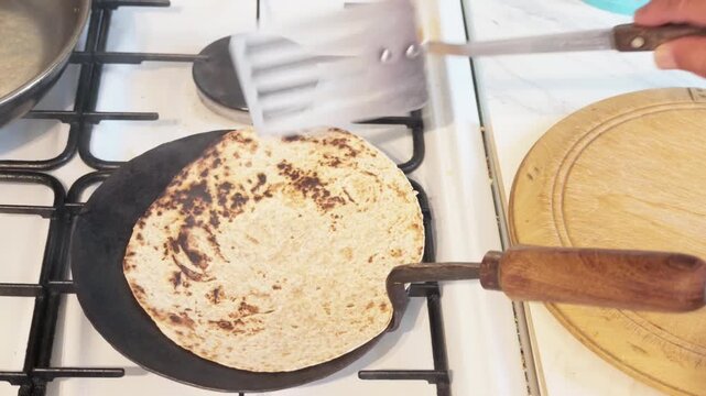 Roti flatbread turned, pressed with a slotted spoon and removed from a hot tava