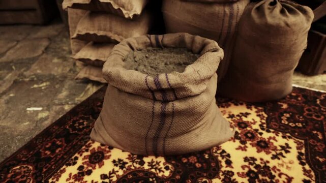 In a lively market setting, burlap sacks filled with colorful spices and grains create an inviting atmosphere. The earthy tones and intricate patterns of the rug add to the charm of the scene.