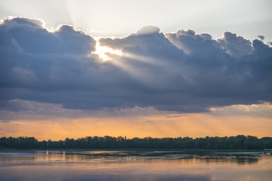 Sunbeams shining through clouds high in the sky during the evening, just before sunset&mdash;a warm, atmospheric landscape for a background