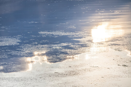 The surface of a lake reflecting the sky, clouds, and the sun in the evening, shortly before sunset&mdash;a minimalist landscape suitable as a background