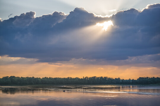 Sunbeams shining through clouds high in the sky during the evening, just before sunset&mdash;a warm, atmospheric landscape for a background