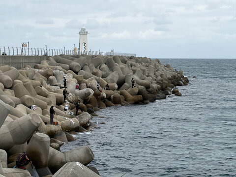 People fishing on tetrapod breakwater with lighthouse in Pohang South Korea