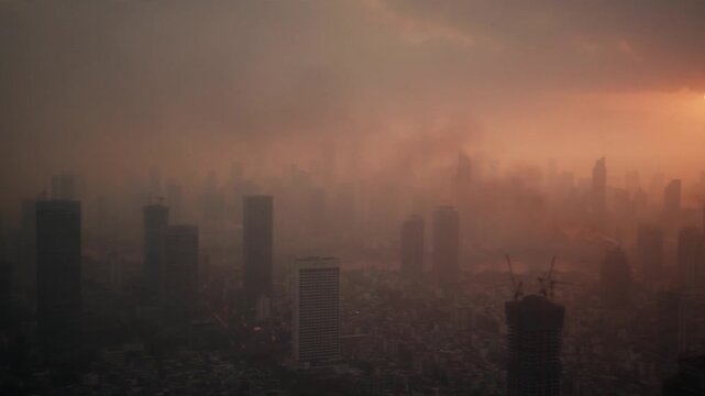 Cinematic View of a Hazy Sunset Over a Dense City Skyline with Heavy Smog and Air Pollution Covering Skyscrapers, Creating a Moody Atmospheric Urban Landscape During Evening Dusk