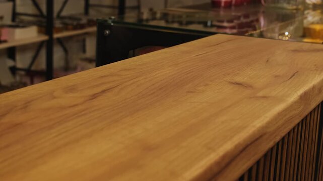 Woman barista wipes wooden countertop with yellow rag in cafe closeup. Female barkeeper hand cleans table surface in modern coffeeshop