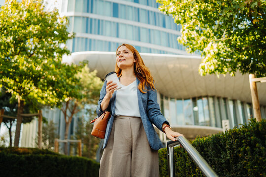Confident businesswoman enjoying coffee outside a modern office building