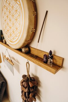 Bohemian wall shelf with hand drum, incense stick, crystals, wind chime, and hanging natural seed ornament in a warm home interior display