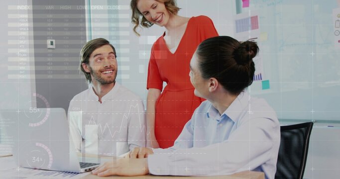 Presenting woman in red dress leaning forward, addressing seated team at office table with laptop