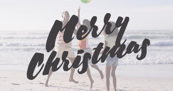 Jumping family reaching for beach ball at sandy shore, orange-shirt child, Merry Christmas text