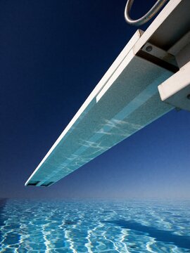 Diving board over a swimming pool against a clear blue sky