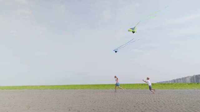 Boy and girl running barefoot with kites on a sandy beach slow motion children at a seaside resort