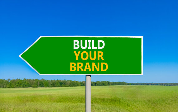 Build your brand words symbol. Concept words Build your brand on beautiful green road sign. Beautiful blue sky green grass background. Business and build your brand concept. Copy space.
