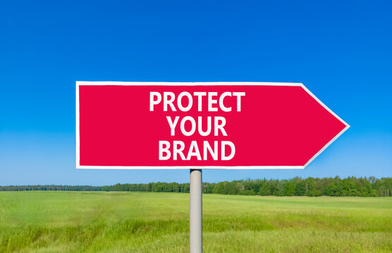 Protect your brand words symbol. Concept words Protect your brand on beautiful red road sign. Beautiful blue sky green grass background. Business and protect your brand concept. Copy space.