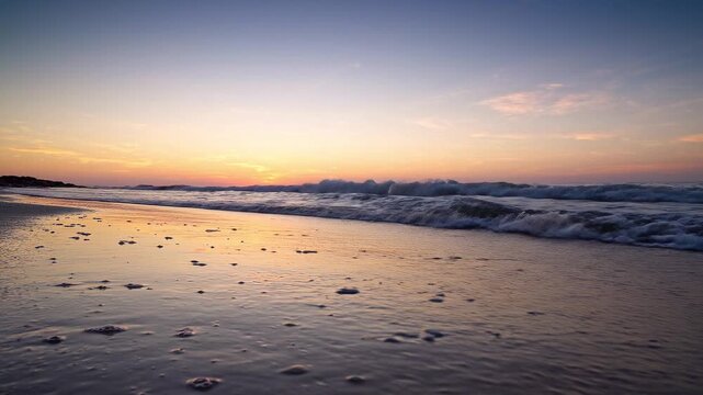 Ocean waves gently lap the sandy shore during a serene sunset with pastel sky colors
