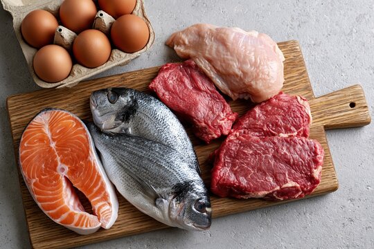 The Assorted Raw Meats on a Wooden Cutting Board with Eggs