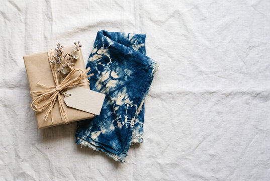 Gift wrapped in kraft paper with dried flowers beside indigo tie dye napkin