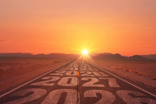 Straight desert road with years 2026, 2027, 2028 painted on asphalt leading into a bright sunrise, symbolizing future journey, goals, time, resolution, development, career path, and new opportunities.