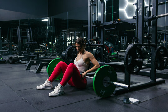 Woman preparing for barbell hip thrusts in a weight training gym