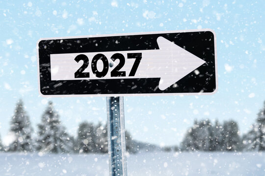 One way road sign with 2027 and arrow pointing right on a snowy winter background during snowfall, representing happy new year direction, future goals, strategy, time, planning, and upcoming changes