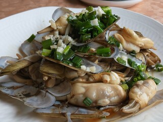 Stir-fried razor clams with minced garlic and green onions served on a white plate © zhu difeng