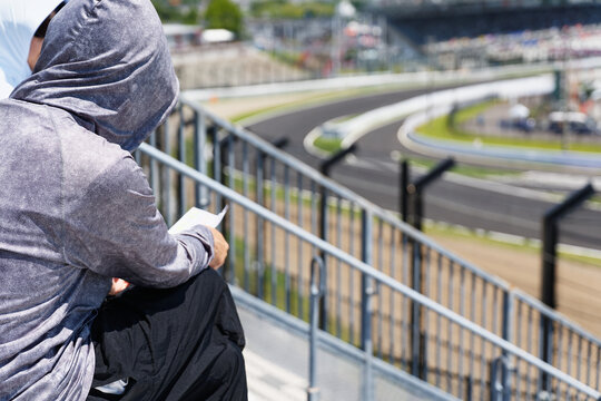Hooded Spectator Seated Beside a Curved Track