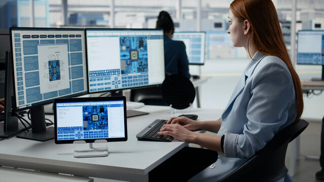 Engineer, tablet and microchip as woman works beside monitors displaying circuit design software. Research, analysis and development drive semiconductor workflow in factory office.