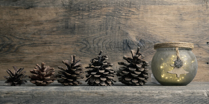 Collection of pine cones in a row with Christmas lights an on a wooden background