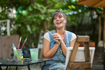 Smiling asian woman artist enjoying creative work outdoors © Wasana