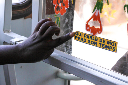 Hand opening a bus window decorated with a French sticker and painted flowers, Sahel Region, Gorom-Gorom, Burkina Faso