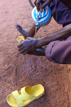Hands pouring water from a kettle onto a foot during ablutions, Hauts-Bassins Region, Bobo Dioulasso, Burkina Faso