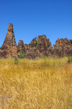 Rock spire of the Sindou Peaks rising above a field of golden grass, Cascades Region, Banfora, Burkina Faso