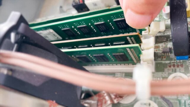 Angled Close Up Of A Hand Removing A RAM Memory Module From A Desktop Motherboard by Releasing A Retaining Clip. Computer Repair and Cleaning , Maintenance, And Hardware Upgrades.