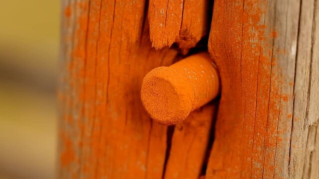 Silver threaded metal bolt inserted into weathered wooden plank in closeup view